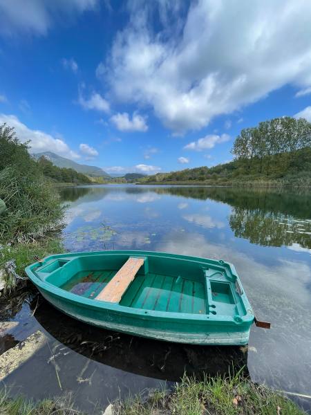 Lac d’Arborias havre de pêche (barque verte attendant au bord d’un lac qui reflète le ciel et la nature environnante)